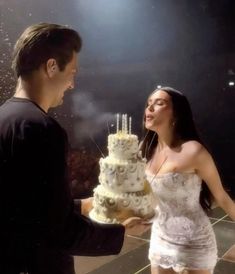 a man standing next to a woman in front of a cake