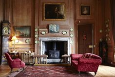 a living room filled with furniture and a fire place in the middle of a wooden paneled wall