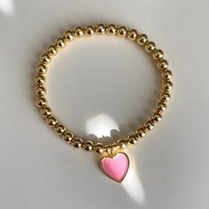 I love this heart charm! Available in pink or pearly white, with 5mm gold filled beads. Charm is 18mm x 12.8mm. This listing is for 1 bracelet only and 5mm gold-filled beads only. Gold-filled beads should not tarnish or fade if handled with proper care. Please read care instructions below. No exchanges or returns. Please contact me anytime with any questions regarding your order. Please measure your wrist before you order, I will not be able to exchange for different sizes at this time. Bracelet Heart-shaped Stretch Bracelet With 8mm Beads As Gift, Heart-shaped 8mm Bead Jewelry Gift, Pink Heart-shaped Beaded Bracelets With Charms, Heart Shaped 8mm Beads Bracelet As Gift, Heart-shaped Bracelet With 8mm Beads For Gift, Heart Shaped 8mm Beads Bracelet Gift, Heart-shaped Bracelet With 8mm Beads As Gift, Pink Round Beads Jewelry For Valentine's Day, Gold Heart-shaped Pearl Bracelet For Valentine's Day