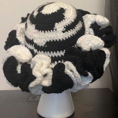 a crocheted hat with black and white flowers on it sitting on top of a table