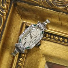 This is a beautifully crafted vintage 18K White Gold Jeweled Swiss made Art Deco watch. Elaborate detailing around the face. Emerald cabochon crown. The top and bottom synthetic emeralds on the left side are chipped, but this does not detract from the watch's overall beauty or functionality. This item is in good condition with only some wear, it has recently been professionally inspected and seems to be running normally. Please review the images provided. Please note, this does not include a ban Emerald Watch, Emerald Art Deco, Emerald Art, Watch Diamond, Art Deco Watch, Watch Women's, Vintage Watches Women, Watches Luxury, Jewelry Lockets