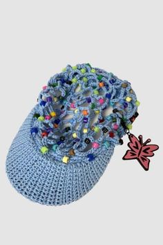 a crocheted blue hat with beads and a leaf brooch on the side