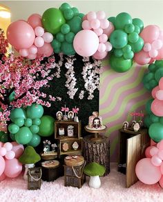 a room filled with lots of balloons and tables covered in pink, green and white decorations