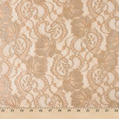 an image of a beige lace fabric with flowers on the bottom and center, as well as a ruler