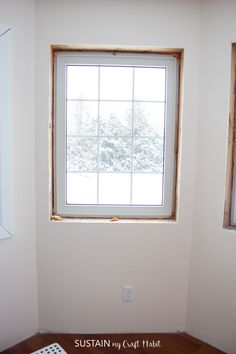 an empty room with a window and wooden floor