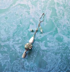 a tasseled keychain hanging from a hook in the water with beads on it