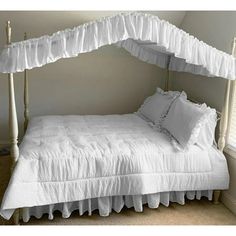 a bed with white ruffled bedspread and pillows