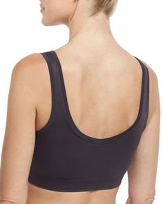 a woman wearing a black sports bra with her back turned to the camera and looking off into the distance