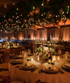 a table set for dinner with candles, plates and napkins on it in an elegant setting