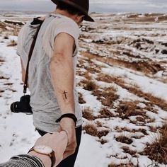 a man walking in the snow with his arm wrapped around another person's hand