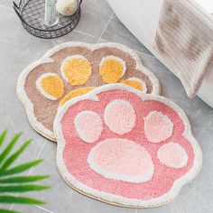 two rugs with paw prints on them next to a potted plant and toilet