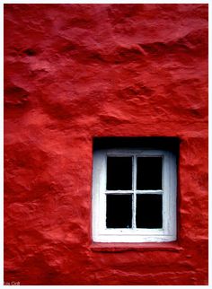 a red building with a white window on it's side and the bottom half is black