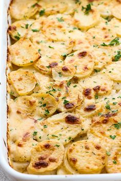 a casserole dish with potatoes and parsley in the middle, topped with cheese