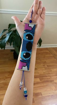 a woman's arm with a beaded bracelet that has the character batman on it