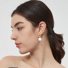 This pair of earrings features a lustrous solitaire shell pearl and a radiant gold hoop, creating a harmonious balance of classic and modern. The delicate huggie hoop is adorned with brilliant pavé set zirconia, adding a touch of sparkle and glamour that beautifully complements the pearls. These earrings effortlessly transition from day to night, from casual to formal events. Whether you're attending a wedding, a dinner party, or simply adding a touch of luxury to your everyday attire, these ear Modern White Pearl Earrings For Everyday, Modern White Round Pearl Earrings, Modern White Single Pearl Earring, Modern Gold Hoop Earrings With Pearl Charm, White Pearl Minimalist Hoop Earrings, Modern White Earrings With Pearl Charm, Trendy White Hoop Earrings With Pearl Drop, White Small Hoop Pearl Earrings Single Earring, Modern Pearl White Earrings With Pearl Charm