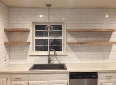 an empty kitchen with white cabinets and open shelving