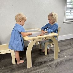 two toddlers playing with their wooden table and chairs