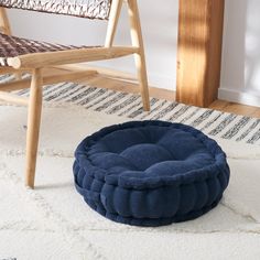 a blue round dog bed sitting on top of a rug next to a wooden chair