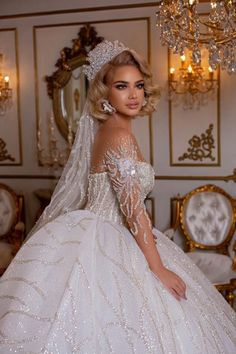 a woman in a wedding dress standing next to a chandelier