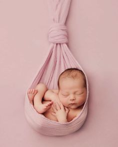 a baby sleeping in a pink hammock with its hands on his chest and eyes closed