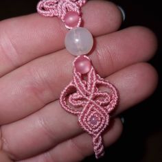 a hand holding a pink beaded bracelet