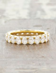 a gold and white diamond ring sitting on top of a wooden table