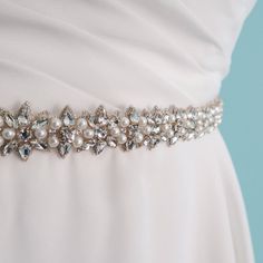 This is a stunning skinny wedding sash belt. This motif on this bridal sash can go well with almost any type of wedding dress. The Swarovski crystals and pearls are disposed in a star like shape and outlining the whole trim is antiqued silver whipstitched thread. The jeweled trim is .86" wide and 24 inches long and it is attached to a silk gazaar ribbon that is  2/3rds of an inch wide. The silk ribbon is bridal white (sometimes called diamond white). It is semi transparent and is also finished w Elegant Bedazzled Bridal Belt For Wedding, Elegant Bedazzled Wedding Sash, Bedazzled Crystal Bridal Belt For Wedding, Crystal Bedazzled Bridal Belt For Wedding, Bedazzled White Bridal Belt For Wedding, Elegant Crystal Wedding Sashes, Elegant Crystal Bridal Belt, Elegant Beaded Bridal Belt, Elegant Pearl Embellished Sashes For Party