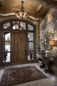 a large wooden door sitting inside of a stone wall next to a table and lamp