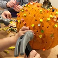 two children are carving a pumpkin with scissors and other crafting supplies on a table