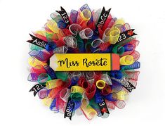 a colorful mesh wreath with the words miss roselle written on it in black and yellow