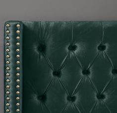 a green leather headboard with gold rivets on the top and bottom buttons