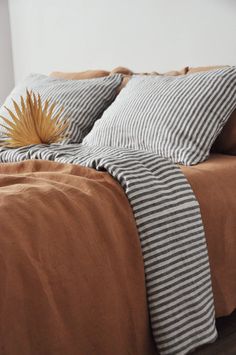 a bed with two pillows on top of it and a plant in the corner next to it