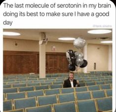 a man is sitting in an auditorium with balloons