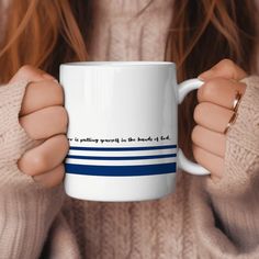 a woman holding a white coffee mug with blue stripes