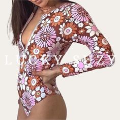 "1970s vintage Flower Power print long sleeve surf women swimsuit. Our charming rash guard one-piece features a high neckline with front zip, soft padding cups, and a cheeky bottom for a \"far out\" surfing babe look. 1970s Floral Print Trendy and flattering vintage style Easy-up front zipper with soft cup pads Covered back with a medium leg and cheeky bottom Imported FIT Fits true to size. To order the best size for you, use the chart provided. Please measure yourself and match your measurement Spring Long Sleeve Surfing Bodysuit, Long Sleeve Floral Print Swimwear For Surfing, One-piece Bodysuit For Spring Surfing, Fitted Long Sleeve Bodysuit With Floral Print, Long Sleeve Floral Print Swimwear For Beach Season, Long Sleeve Swimwear For Surfing In Summer, Long Sleeve Bodysuit For Poolside And Beach Season, Poolside Long Sleeve Bodysuit For Beach Season, Long Sleeve Beachwear Swimwear For Spring