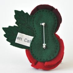 a green and red brooch sitting on top of a white table next to a name tag