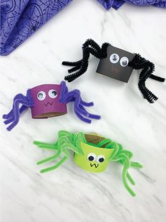 three paper cups with googly eyes and spider faces on them sitting on a marble surface