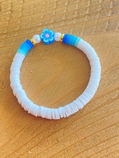 a blue and white flower bracelet on a wooden surface with beads in the shape of flowers