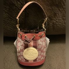 Nwt, Never Used. Beautiful Burgundy, Color With Pink Handle And Accents. On-the-go Bucket Bag In Coated Canvas, Coated Canvas Bucket Satchel, Coach Travel Bucket Bag With Gold-tone Hardware, Coach Beige Bucket Bag, Coach Beige Bucket Bag With Removable Pouch, Coach Satchel Bucket Bag With Removable Pouch, Coach Beige Bucket Bag For Shopping, Coach Travel Crossbody Bucket Bag, Coach Crossbody Bucket Bag For Travel