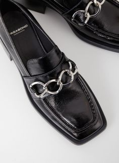 BLANCA black patent loafer with a striking oversized silver-tone chain by Swedish shoe brand Vagabond Shoemakers. Blanca is a dressy heeled loafer crafted in polished black patent leather, with a silver-tone chain detail, square toe and decorative stitched seams across the vamp. A 2-inch flared heel for a subtle lift. This loafer is an edgy day-to-night staple shoe for your wardrobe and works well with everything from shift dresses, vintage flared pants, LBD's, and distressed denim. Wear this shoe all year round with bare feet or hidden no-show socks this spring and with socks or tights on cooler days. The sheen and chunky silver chain detail make this black loafer look very rich and expensive. Make them do a double take! Gucci who? - Upper: Black Patent Leather - Silver-Tone Chain Detail