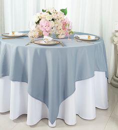 a blue table cloth with white and pink flowers on it sits in front of a window