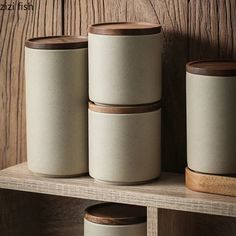 three ceramic containers are sitting on a shelf next to a wooden box with two lids