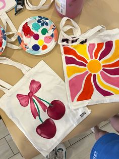 three bags with designs on them are sitting on the table next to plates and cups