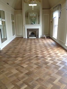 an empty room with hard wood flooring and a chandelier hanging from the ceiling