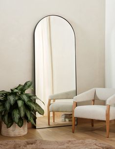 a mirror sitting on top of a wooden floor next to a chair and potted plant