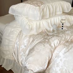 a bed with white comforters and pillows on top of each other in a bedroom