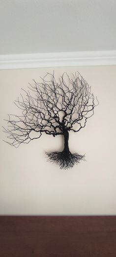 a black tree with roots hanging on the wall