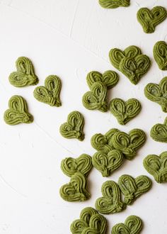 several green heart shaped cookies on a white surface