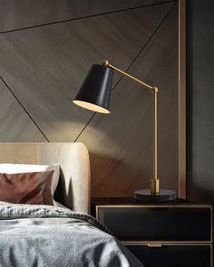 a bed sitting next to a night stand with a black lamp on top of it