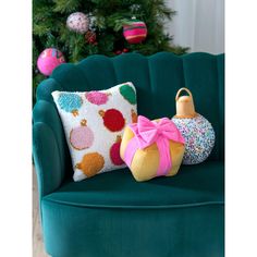 a green chair with two pillows on it and a christmas tree in the background